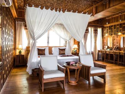 Lichte hotelkamer met hemelbed, twee stoelen en houten constructie