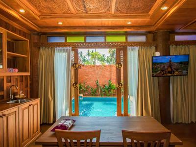 Interieur met houten meubels en uitzicht op een zwembad door een open deur.