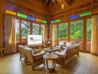 Lichte woonkamer met houten meubels en grote kleurrijke ramen in een lodge.