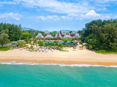 Strandresort met zwembad, ligstoelen en groen onder een blauwe lucht.