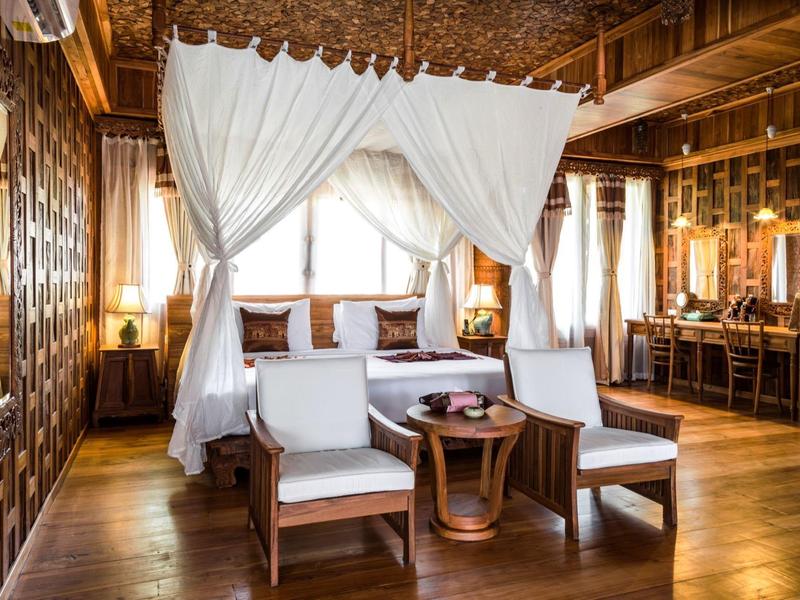 Lichte hotelkamer met hemelbed, twee stoelen en houten constructie