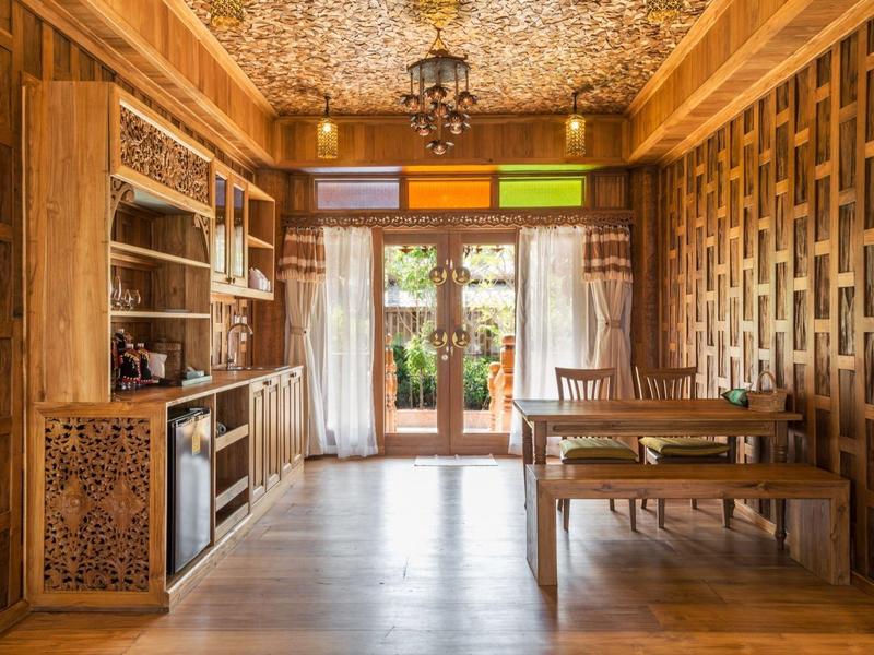 Gezellige eetruimte met houten meubels, kasten en glazen deuren naar de tuin.