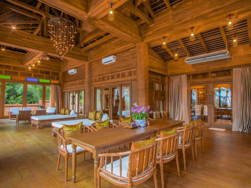 Ruime eetkamer van hout met tafel, stoelen en sfeerverlichting.