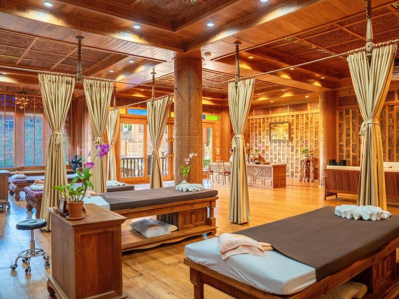 Gezellig spa-ruimte met houten plafond, gordijnen en massagetafels in warm licht.