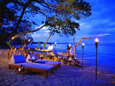 Przytulne meble wypoczynkowe i pochodnie na plaży o zachodzie słońca nad morzem.