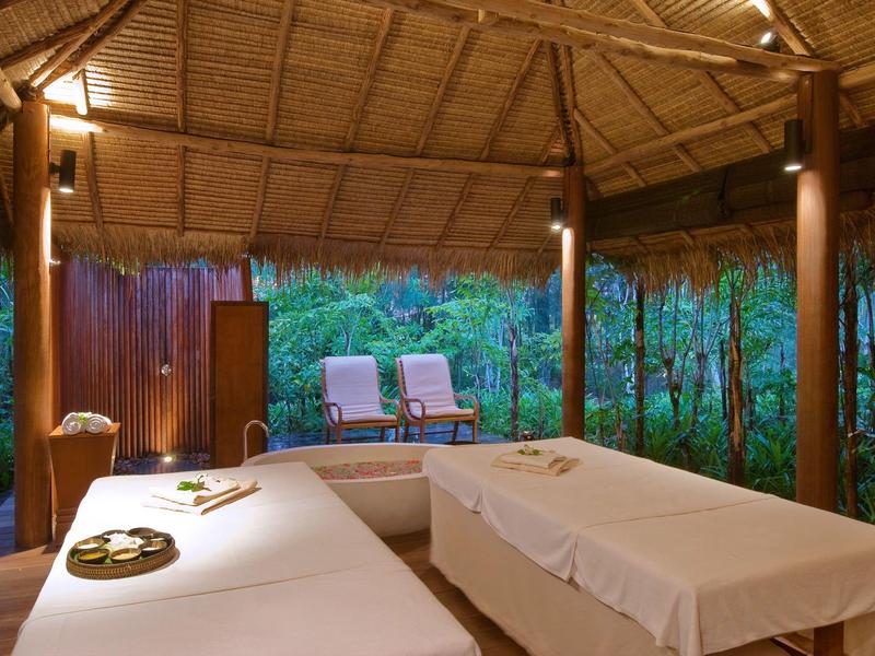 Otwarta przestrzeń do masażu z dwoma stołami do masażu i leżakami w naturalnym otoczeniu.