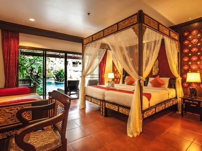 Elegantes Hotelzimmer mit Himmelbett, Sesseln und Zugang zu einer Terrasse mit Gartenblick.