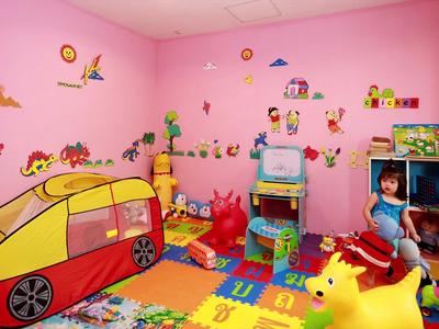 Buntes Kinderspielzimmer mit rosa Wänden, Spielzeugauto, Matten und diversen bunten Spielsachen.