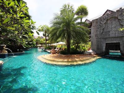 Tropischer Pool mit Insel, Palmen und Felsen im Hotelresort.