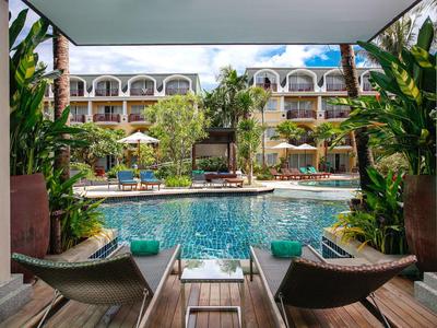 Vista da una terrazza coperta su una piscina con lettini in un hotel su più piani.