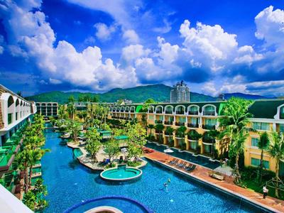 Resort di lusso con più piscine, circondato da colline verdi e cielo azzurro.