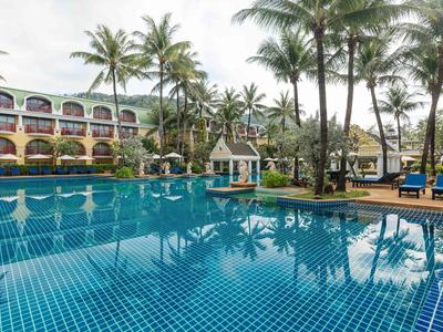 Duży basen hotelowy z palmami i leżakami w tropikalnym otoczeniu