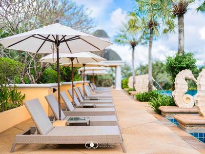 Leżaki pod parasolami obok basenu w tropikalnym hotelu