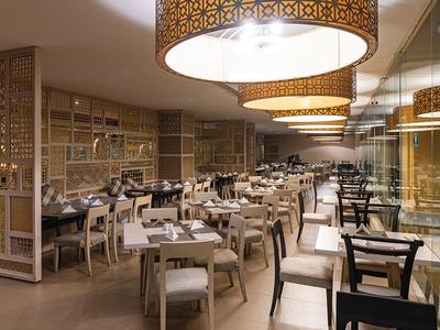 Ristorante moderno dell'hotel con mobili chiari e lampade decorative a soffitto.