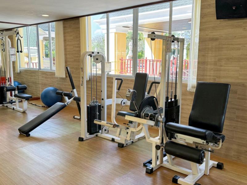 Palestra moderna con varie attrezzature per forza e cardio di fronte a grandi finestre.