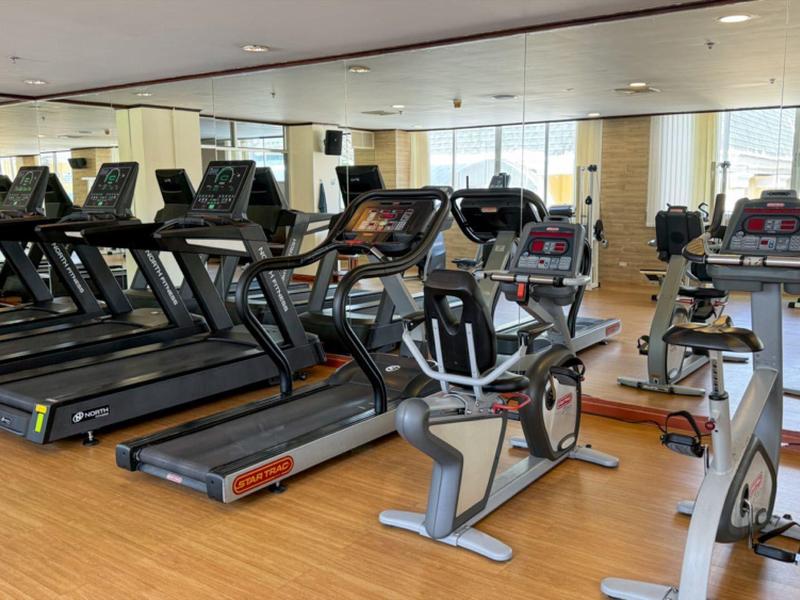 Palestra luminosa con tapis roulant e cyclette davanti a uno specchio grande