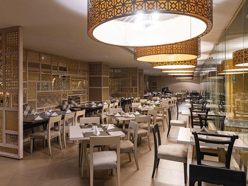 Ristorante moderno dell'hotel con mobili chiari e lampade decorative a soffitto.