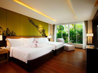 Moderní hotelový pokoj se dvěma velkými postelemi, dřevěnou podlahou a výhledem na zelenou zahradu.