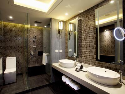 Moderní koupelna s dvojitým umyvadlem, osvětleným zrcadlem a skleněnou sprchou.