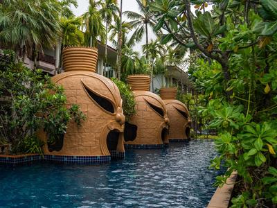 Piscine avec des structures uniques en forme de jarre de couleur terre cuite et une végétation luxuriante.
