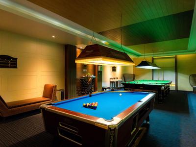 Intérieur avec deux tables de billard sous un éclairage chaud dans un espace de loisirs.