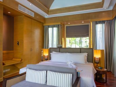 Moderní hotelový pokoj s velkou postelí, dřevěným nábytkem a výhledem na zahradu.