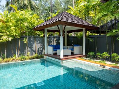 Moderní pavilon s posezením vedle čistého modrého bazénu v tropickém prostředí.