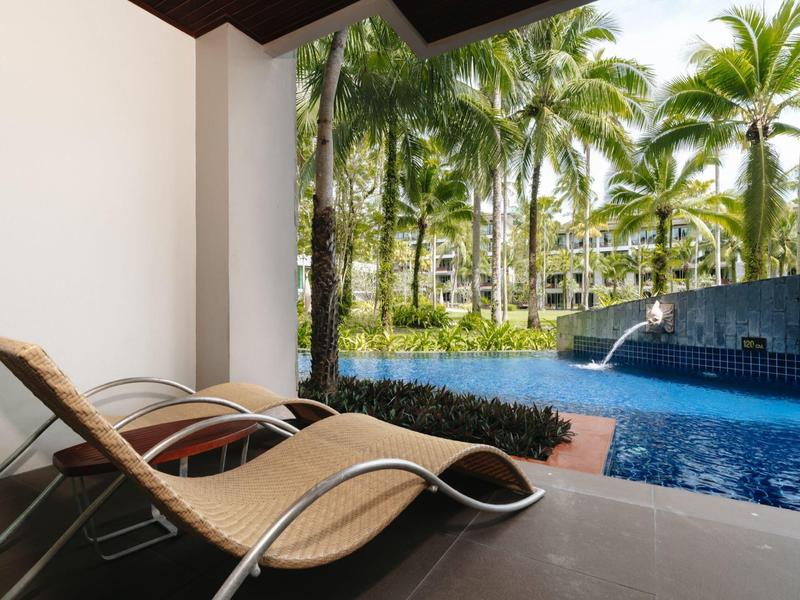 Dvě lehátka na terase s výhledem na bazén a palmy.