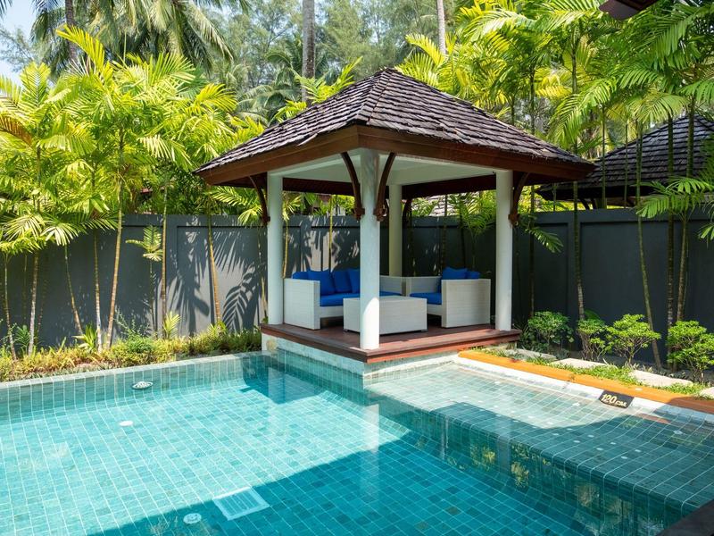 Moderní pavilon s posezením vedle čistého modrého bazénu v tropickém prostředí.