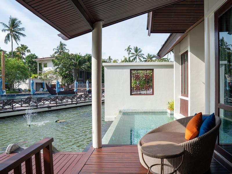 Pohled z verandy na soukromý bazén s výhledem na vodní kanál a palmy.