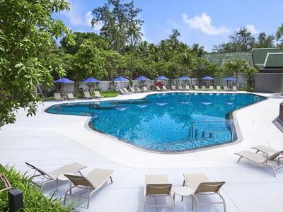 Piscina moderna con lettini e ombrelloni in un ambiente alberghiero.