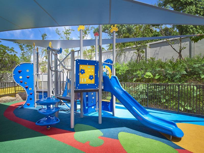 Bunter Spielplatz mit Rutsche, Klettergerüst und schattenspendendem Dach im Freien.