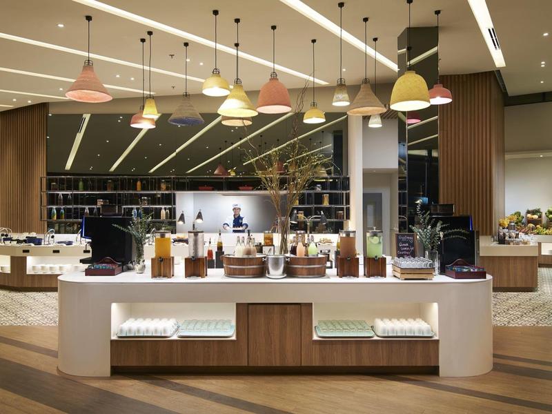 Moderner Gastrobereich mit beleuchtetem Buffet, Holzverkleidung und bunten Hängeleuchten.