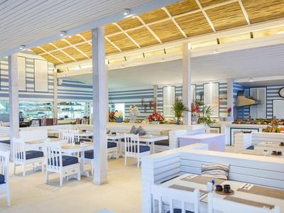 Helles, modernes Restaurant mit weißen Holzmöbeln und großen Fenstern für Tageslicht.