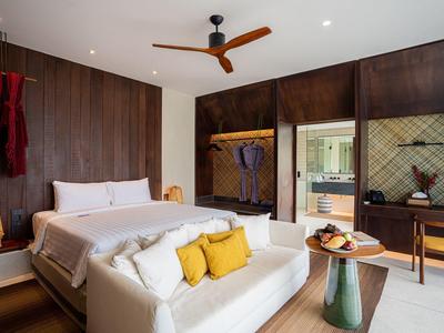 Modernes Schlafzimmer mit Holzwänden, weißem Bett, gelben Kissen und Deckenventilator aus Holz.