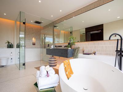 Moderner, heller Badezimmer mit freistehender Badewanne, Glasdusche und großem Spiegel.