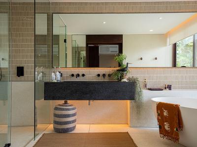 Moderner Badbereich mit grauem Doppelwaschtisch, Badewanne und großen Fenstern, helle Fliesen an Wand.
