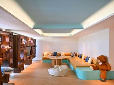 Gemütlicher Kinderspielbereich mit bunten Sitzgelegenheiten und großen Teddybären in einem modernen Raum.