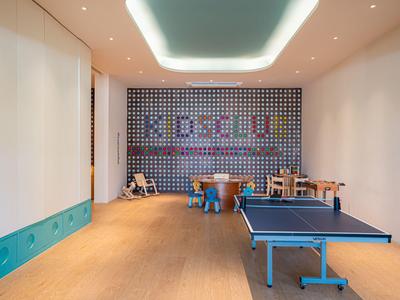 Ein moderner Spielbereich mit Tischtennisplatte, bunten Sitzmöbeln und einem Wandbild im Hotel.