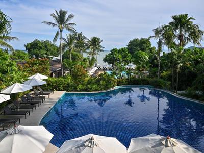Großer Pool mit blauer Wasseroberfläche, umgeben von Sonnenschirmen, Liegestühlen und Palmen.