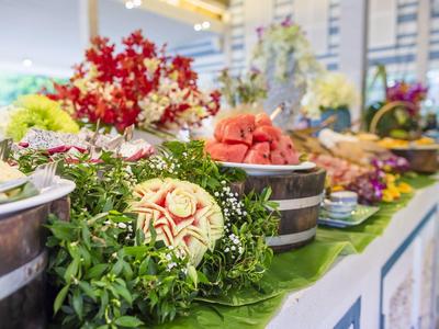 Ein bunter Buffet-Tisch mit Obst, Blumen und dekorativen Elementen in einer hellen Umgebung.