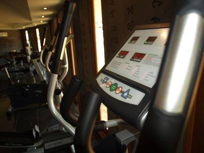 Nahaufnahme eines modernen Crosstrainers mit digitalem Display und silbernen Griffen im Fitnessstudio.
