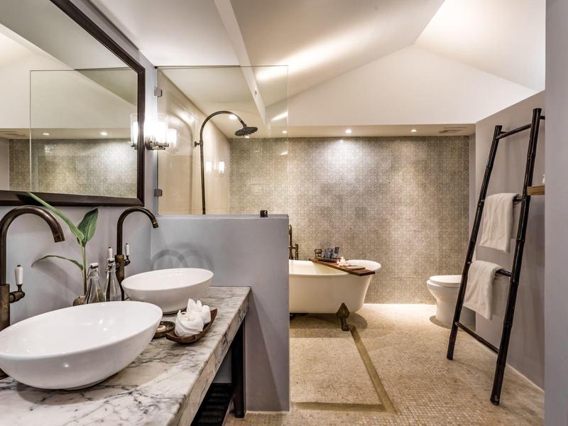 Nowoczesna łazienka z wolnostojącą wanną, podwójną umywalką i drabinką na ręczniki.