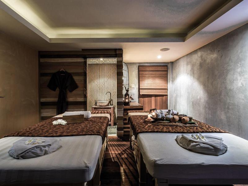 Dwa łóżka do zabiegów w stylowym pokoju spa z przyciemnionym oświetleniem i spokojną atmosferą.