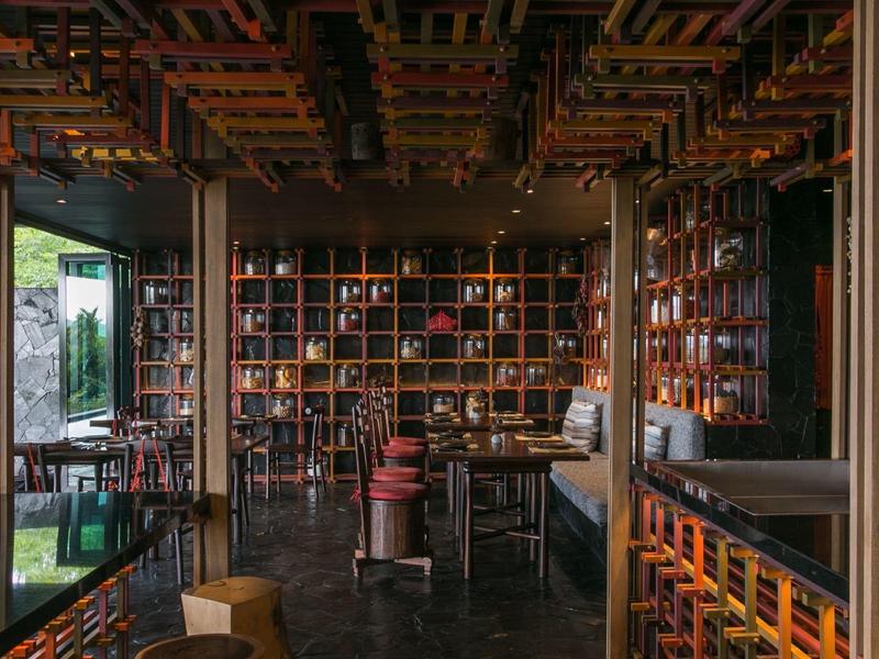 Przytulny bar hotelowy z drewnianymi półkami, miejscami do siedzenia i ciepłym, przytłumionym światłem.