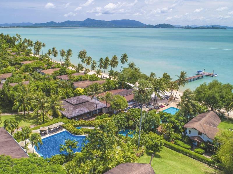 Luksusowy kurort nadmorski z willami, basenem i palmami przy turkusowym morzu.