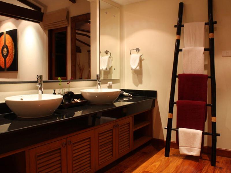 Nowoczesna łazienka z dwoma umywalkami, drewnianymi meblami i drabinką na ręczniki.