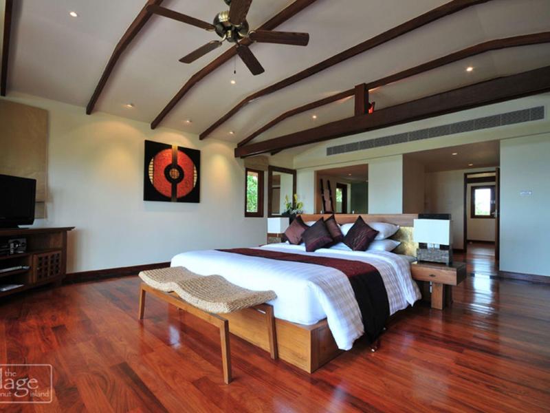 Przestronna sypialnia z łóżkiem podwójnym, drewnianą podłogą i wentylatorem sufitowym w obiekcie.