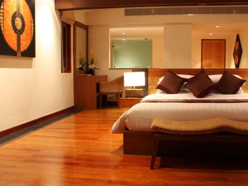 Nowoczesny pokój hotelowy z drewnianą podłogą, dużym łóżkiem i klimatycznym oświetleniem.