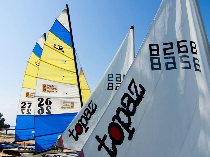 Żaglówki z kolorowymi żaglami na plaży pod czystym niebem.